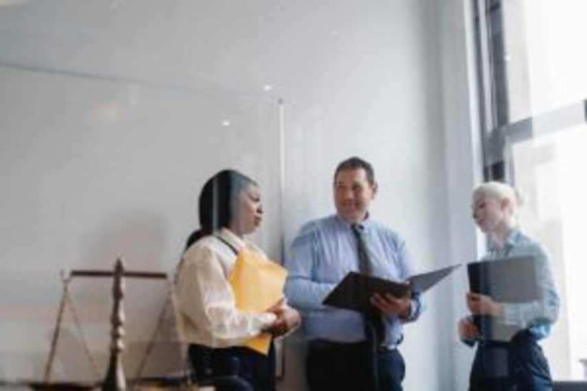 Three staff members chat while standing in an office