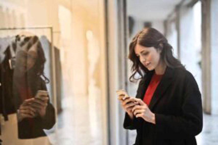 A woman browses information on the phone outside a store