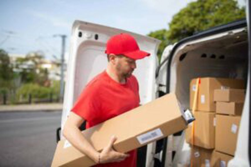 A man sorting boxes of goods from a van