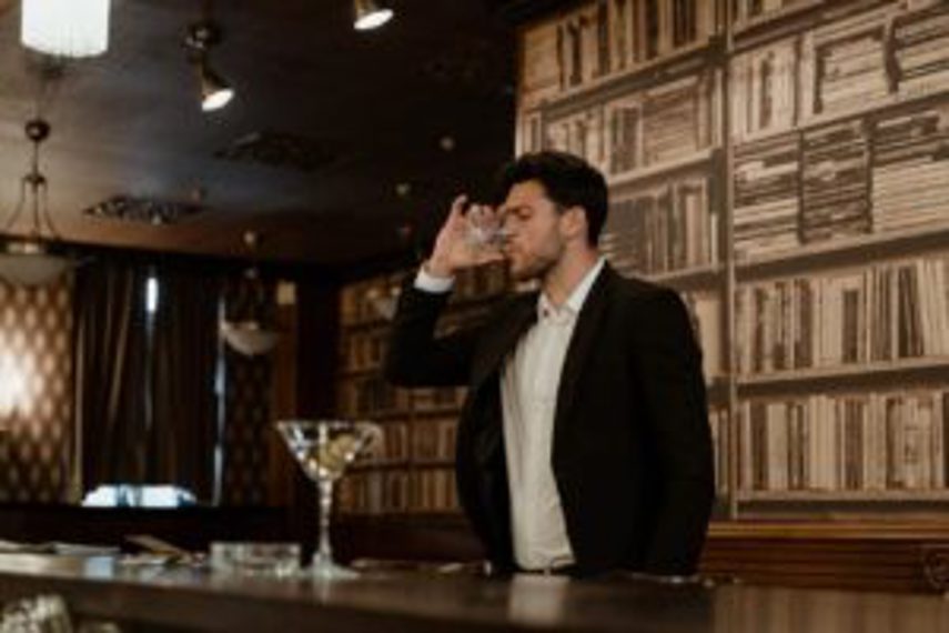 A man drinks whisky at a bar