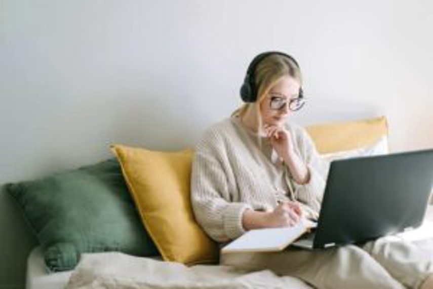 A girl sits at her laptop with a notebook