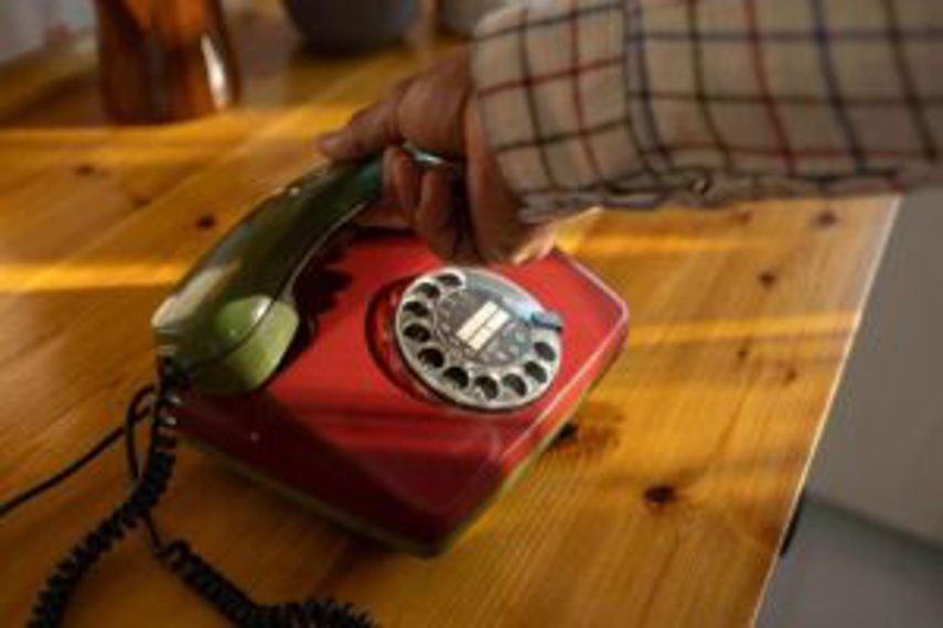 A person picks up the headset of a landline phone