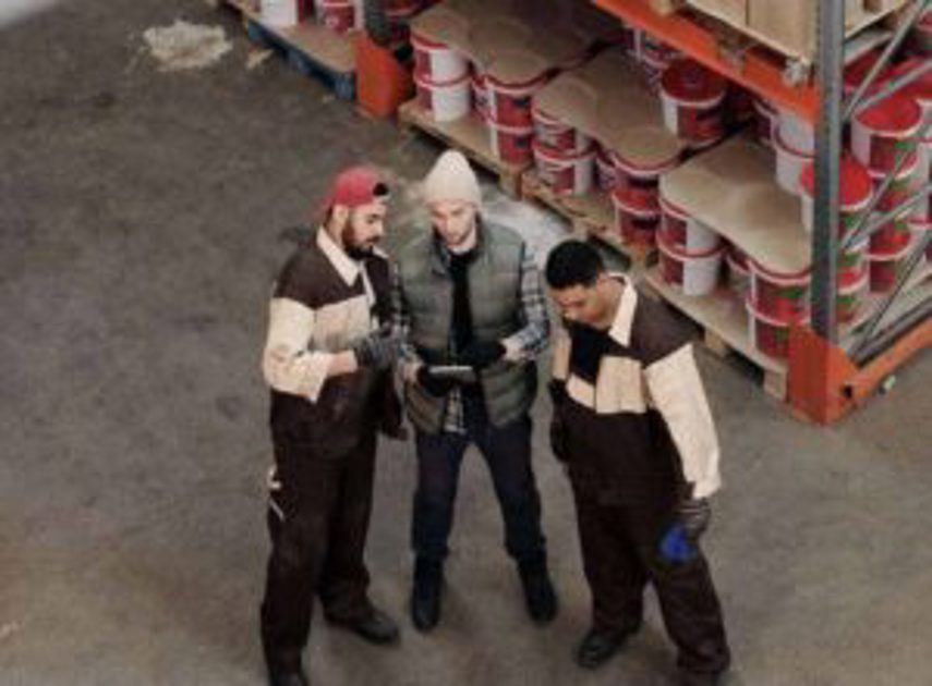 Three men look at a tablet in the warehouse