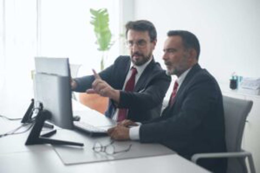 Two men viewing inventory metrics on a computer