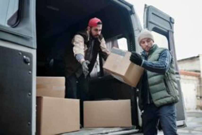 Two men unload boxes from the back of a van