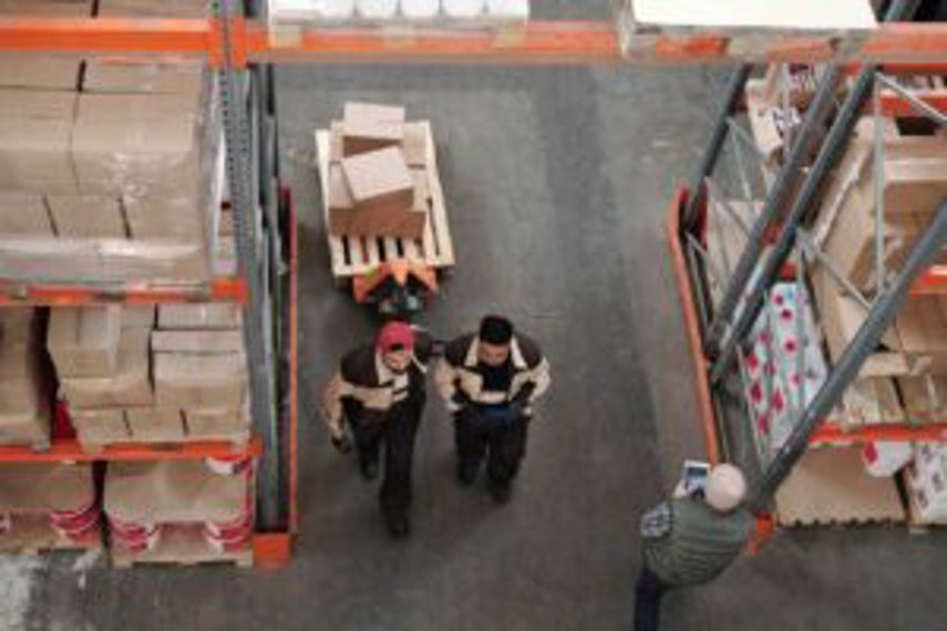 Two men pull a cart in a warehouse