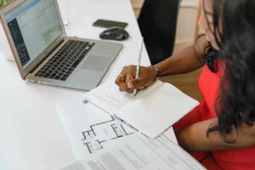 A woman takes notes and reads plans at a desk