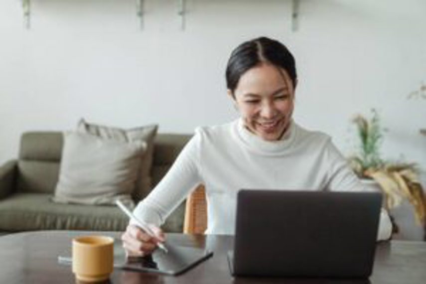 A woman works at her computer and takes notes