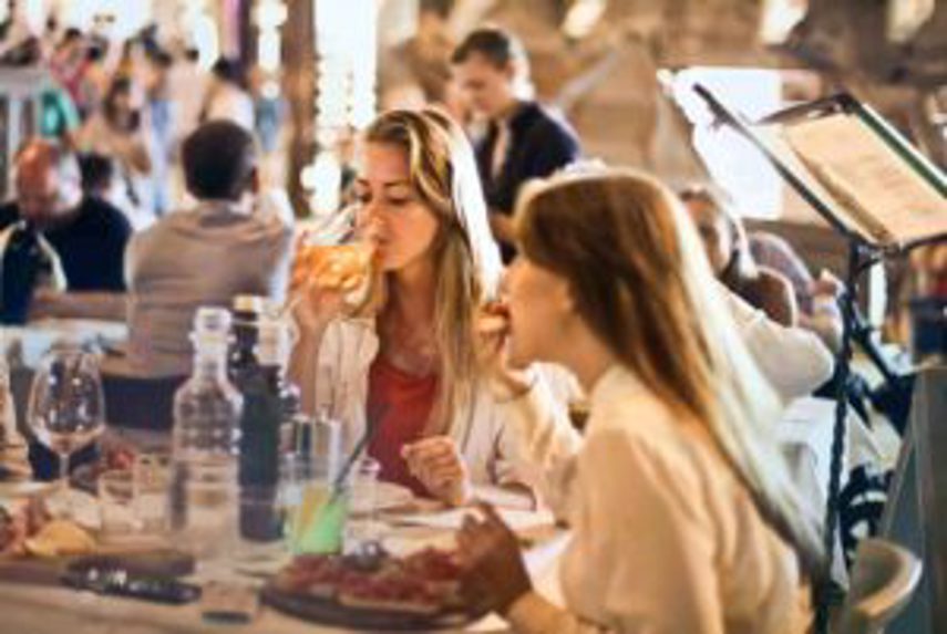 Two women drinking wine and eating at restaurant