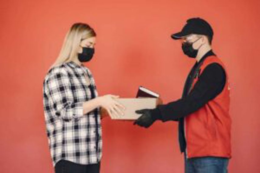 A delivery man passes a package to a woman