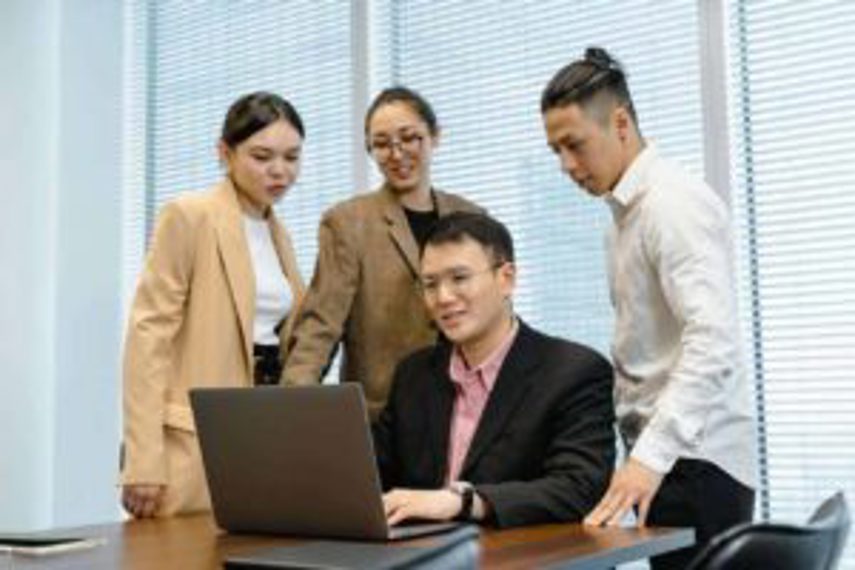 Several people looking at a man's laptop.