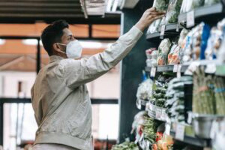 A man reaches for goods in the vegetable section of a supermarket