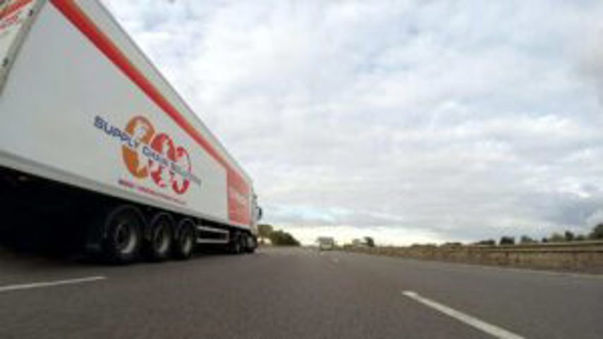 A supply chain solutions truck driving down a highway