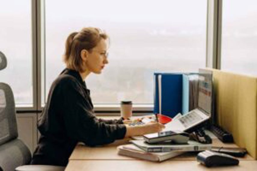 A woman works at her desk with calculator and computer