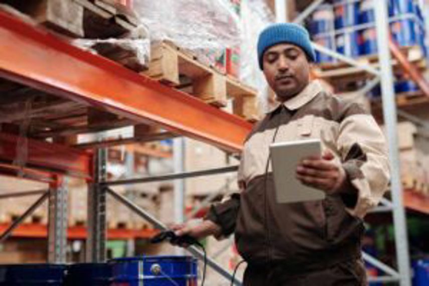 A man uses a tablet in the warehouse to manage stock