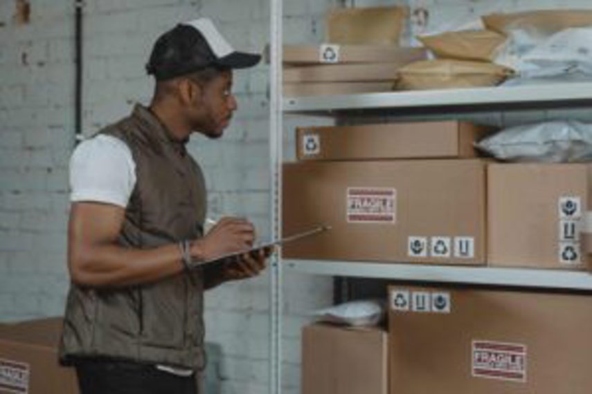 A man checks boxes of goods stacked up on shelves